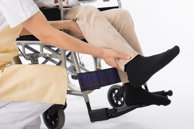 男性の足を車椅子に乗せるスタッフ